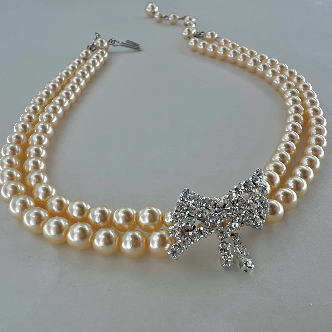 Halskæde, choker med beige voksperler og sløjfe vedhæng, forsølvet messing Beadhouse of Copenhagen